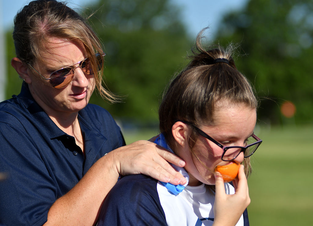 McKenna Edwards, 13, eats an orange while coach Barb Loyd places a wet towel on the back of her neck